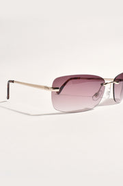 A pair of rimless, full frame sunglasses with purple lenses and gold-colored frames.