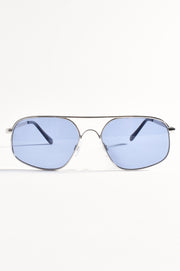 Aviator-style sunglasses with silver frames and blue lenses placed on a white surface.