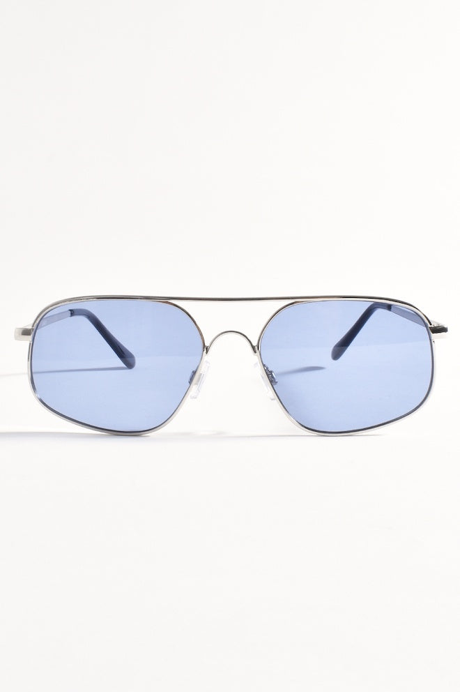 Aviator-style sunglasses with silver frames and blue lenses placed on a white surface.