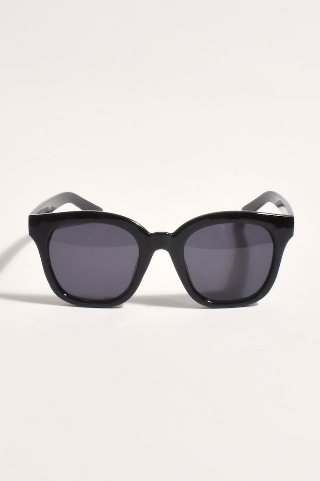 A pair of black full frame sunglasses with dark lenses, positioned to show the front profile.