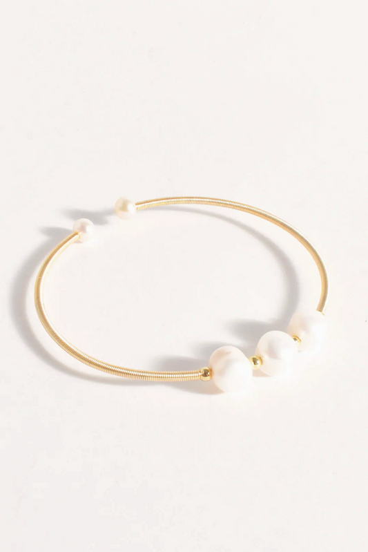 Gold necklace with white beads on a light gray background