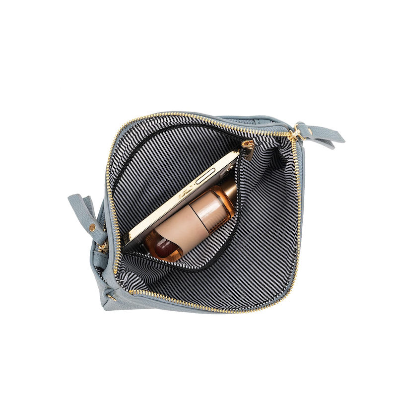 Gray cosmetic bag with a black interior, containing a bottle of foundation.