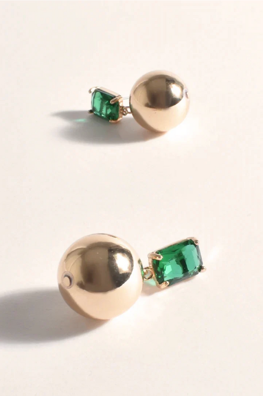 Gold earrings with green gemstones on a light background