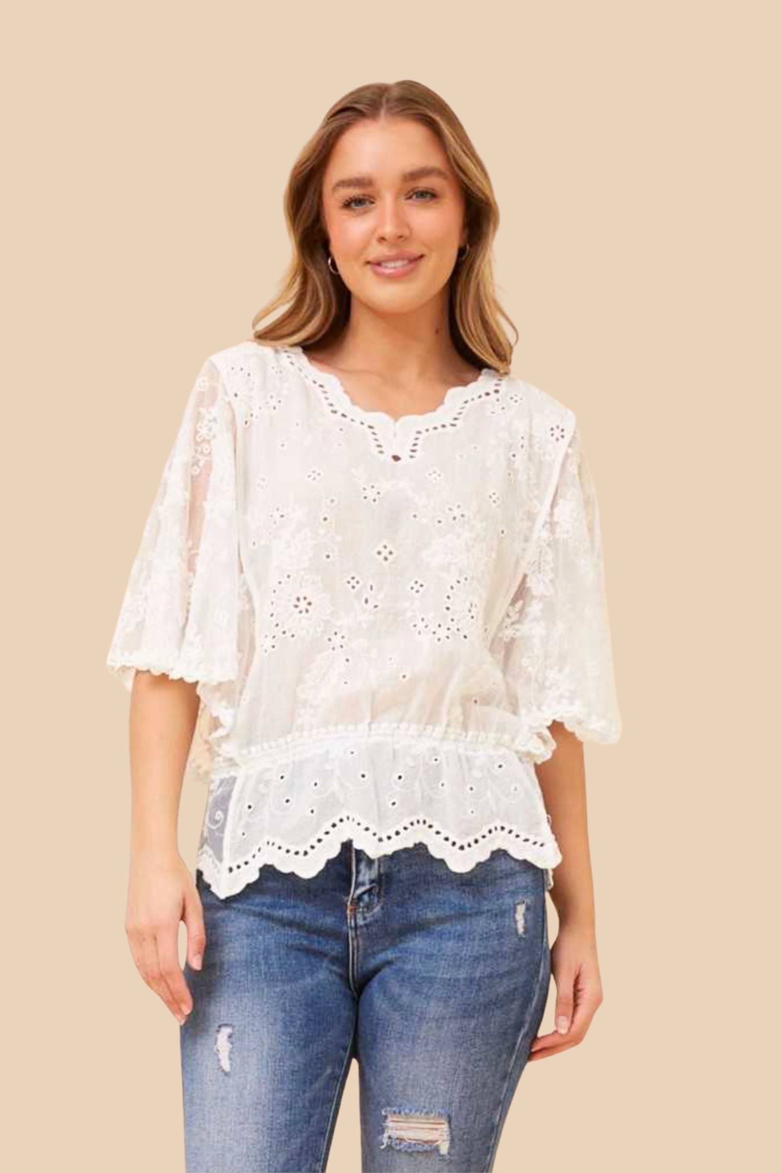 Indie Lace Top by Caroline K Morgan — front view of white broderie anglaise lace top with flutter sleeves, scalloped hem and elasticated waist, styled with blue distressed jeans, available in Australia at Kat and Ko Clothing