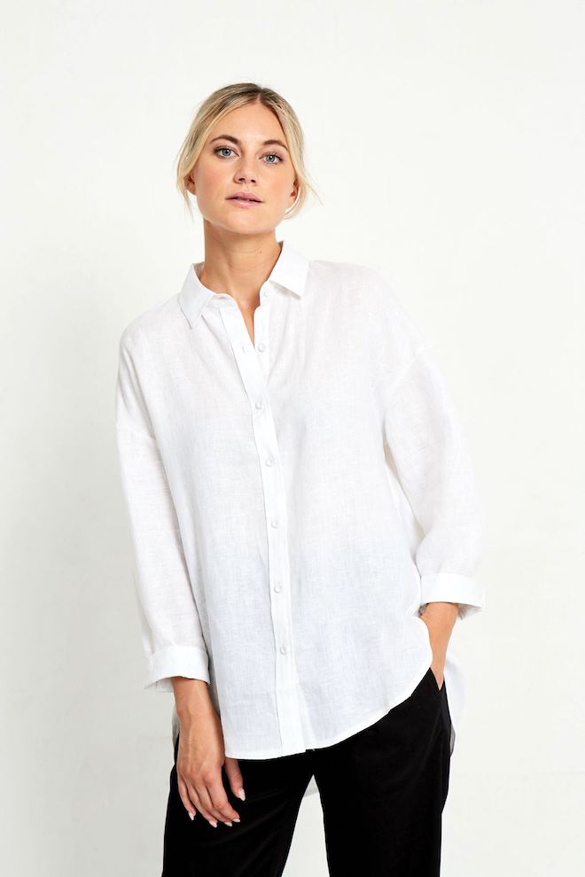 Person wearing a white shirt and black pants against a plain background