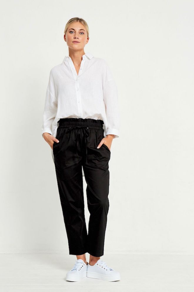 Woman wearing a white shirt and black pants on a white background