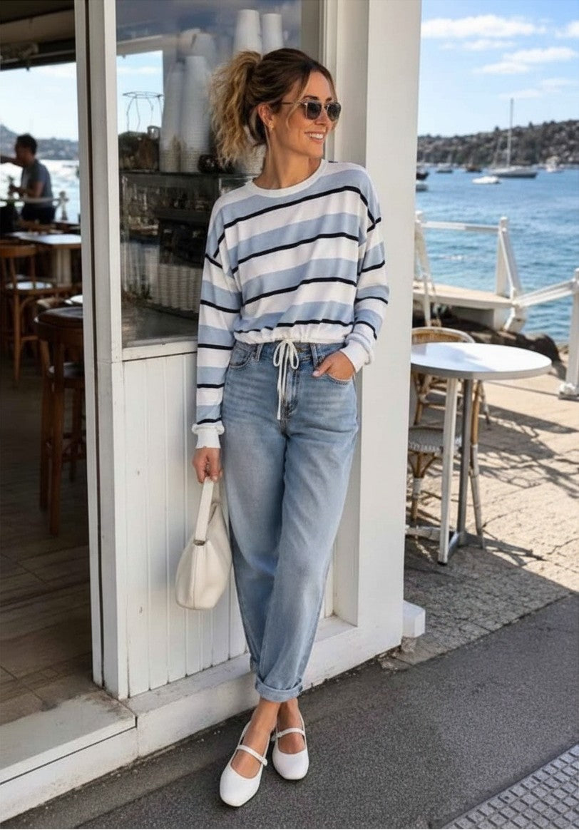 Kat and Ko Clothing Hailey blue striped cotton top with drawstring hem worn by a woman with jeans and white shoes