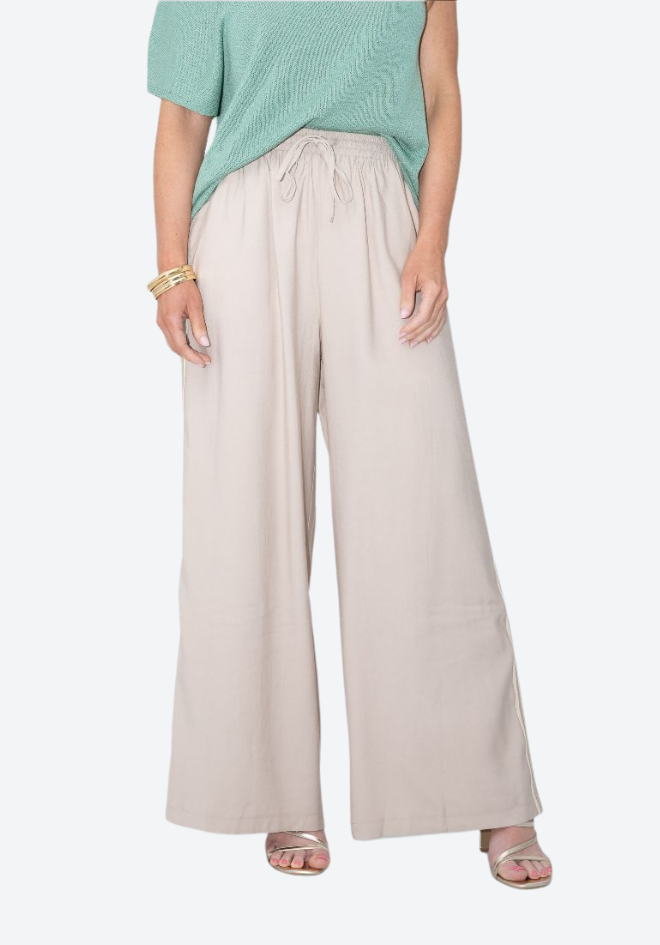 Person wearing light beige wide-leg pants with a green top on a white background