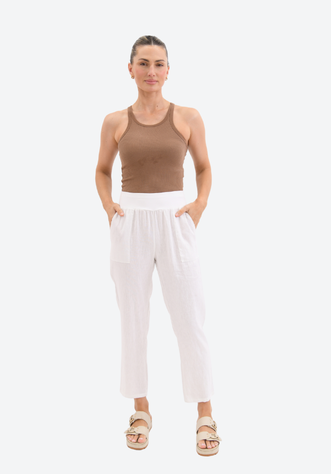 Woman wearing a brown tank top and white pants on a white background