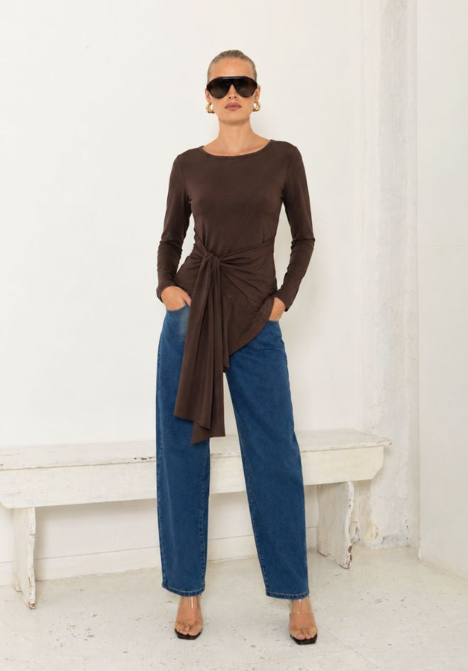 Veronique Top by Ave The Label — full-length front view of chocolate brown long sleeve top with adjustable tie waist detail, styled with wide-leg blue jeans and heels, available in Australia at Kat and Ko Clothing