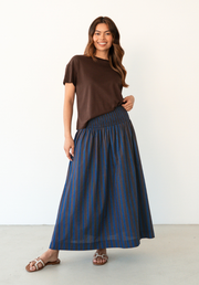 Charli Skirt by Label of Love — full-length front view of chocolate and cobalt blue stripe cotton maxi skirt with shirred waistband, styled with a brown tee and sandals, available in Australia at Kat and Ko Clothing