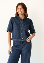 Collette Chambray Shirt by Label of Love — front view of cropped dark blue lyocell chambray shirt with button-through front, chest pocket and short sleeves, styled with matching wide-leg pants, available in Australia at Kat and Ko Clothing