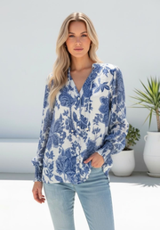 Lara Blouse by Miracle — front view of blue and white floral print blouse with V-neckline, button placket and shirred wristband sleeves, styled with light denim, available in Australia at Kat and Ko Clothing