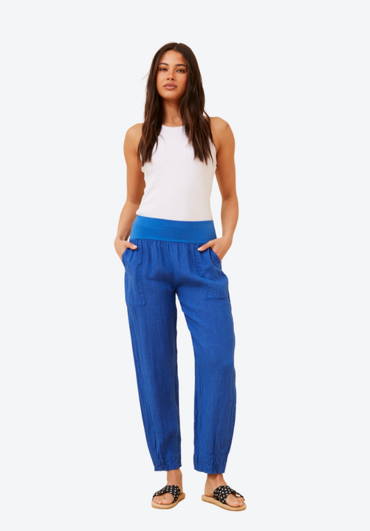 Woman wearing blue pants and a white top on a white background