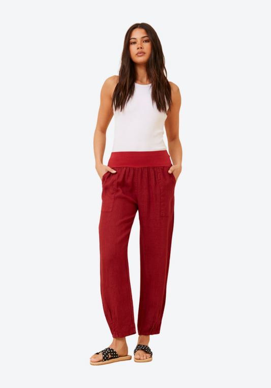 Woman wearing red pants and a white top on a white background