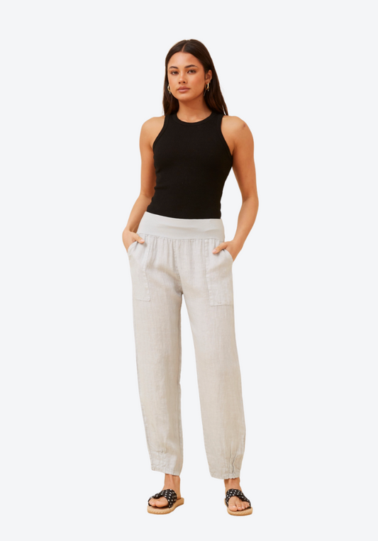 Woman wearing a black sleeveless top and beige pants on a white background
