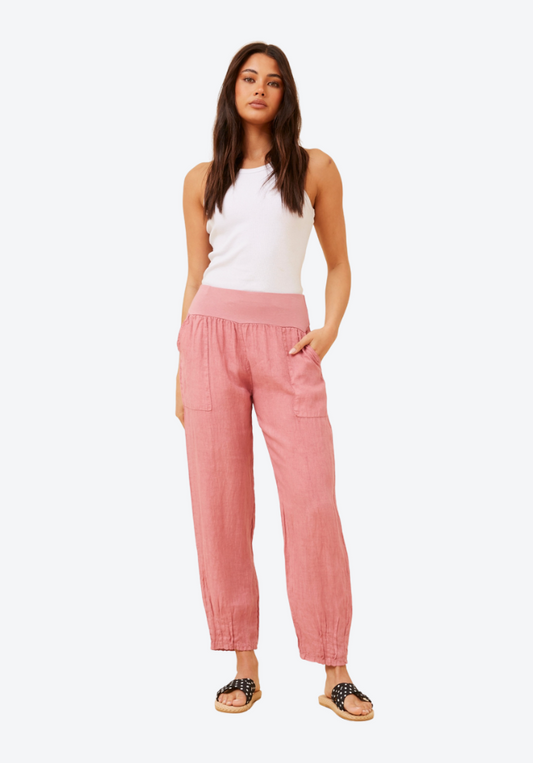 Woman wearing a white top and pink pants on a white background