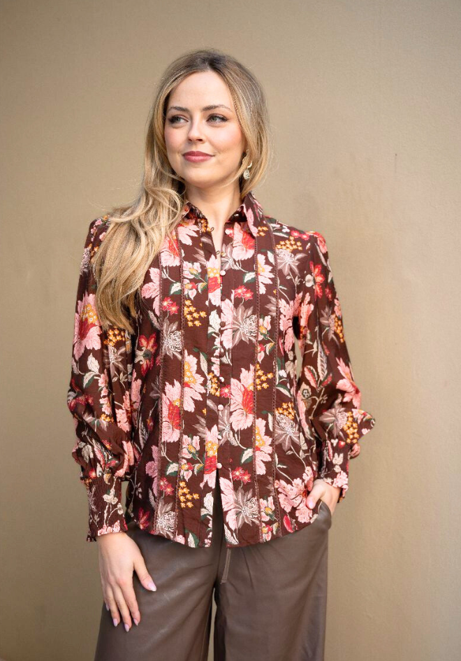 Woman wearing a floral blouse against a beige background