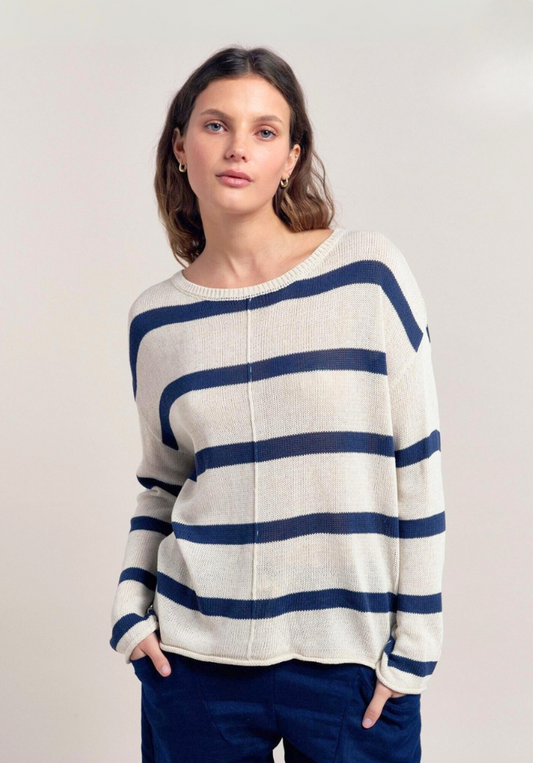 Woman wearing a white sweater with blue stripes against a plain background