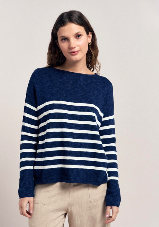 Woman wearing a navy and white striped sweater against a plain background