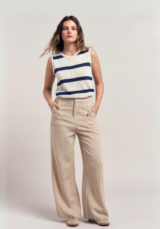 Woman wearing a sleeveless striped top and beige pants on a plain background