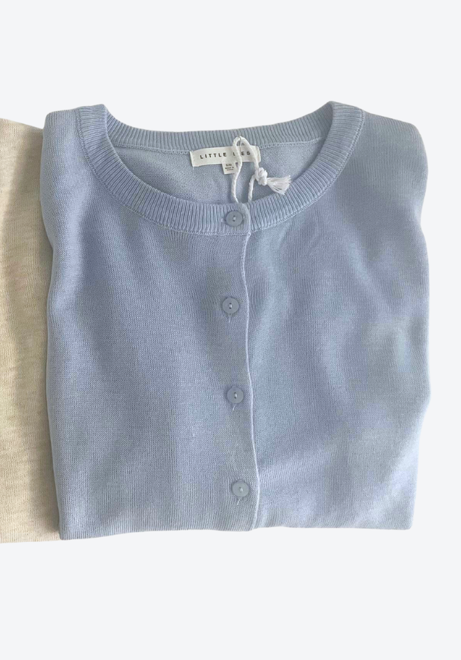 Folded light blue cardigan on a white background