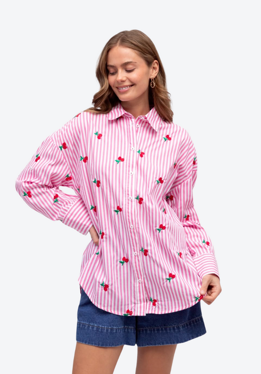 Woman wearing a pink striped shirt with cherry pattern on a white background