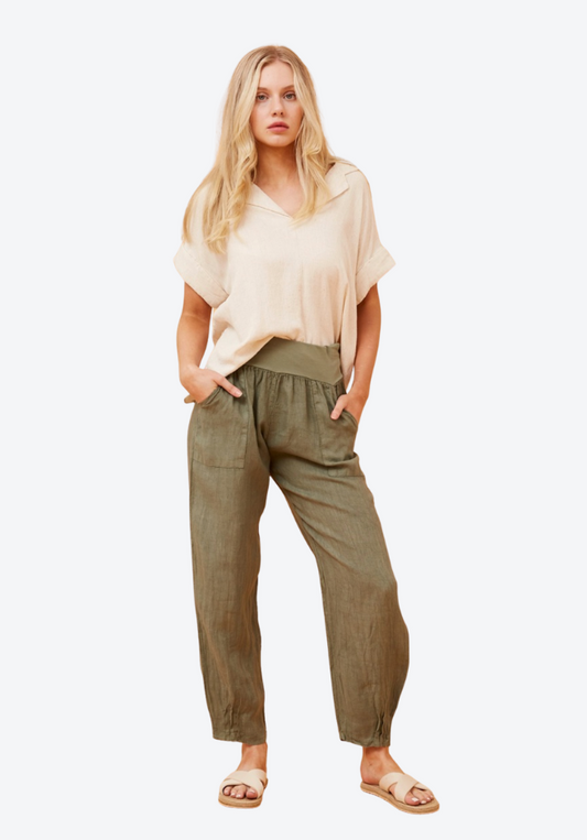Woman wearing a beige top and olive green pants on a white background