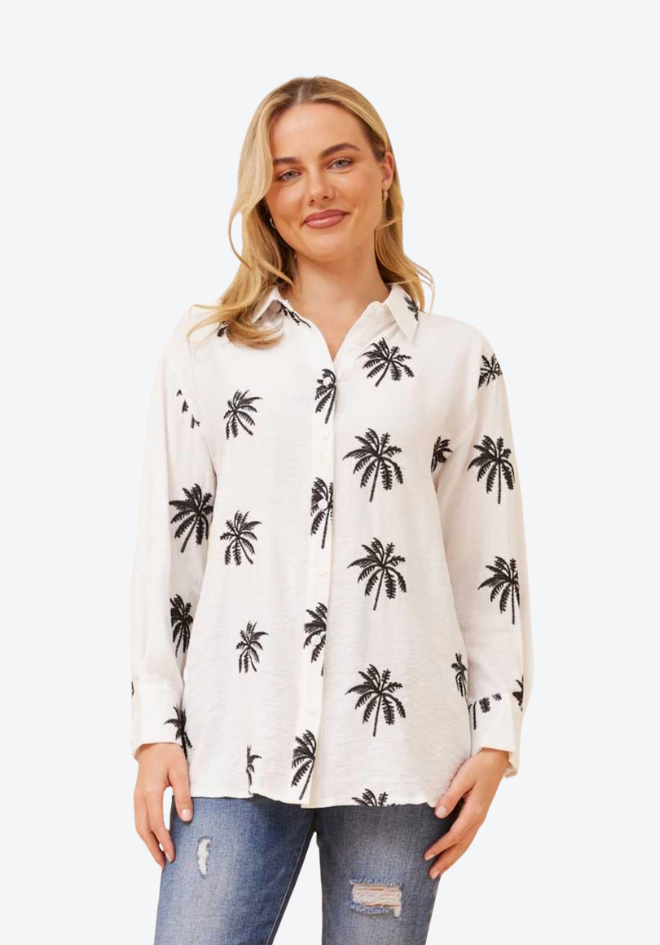 Woman wearing a white shirt with black palm tree pattern on a white background