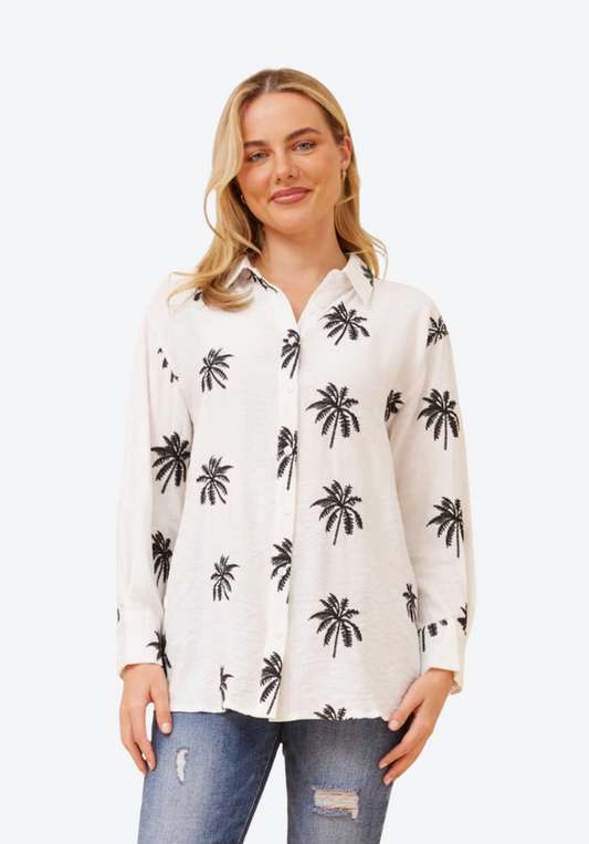 Woman wearing a white shirt with black palm tree pattern on a white background
