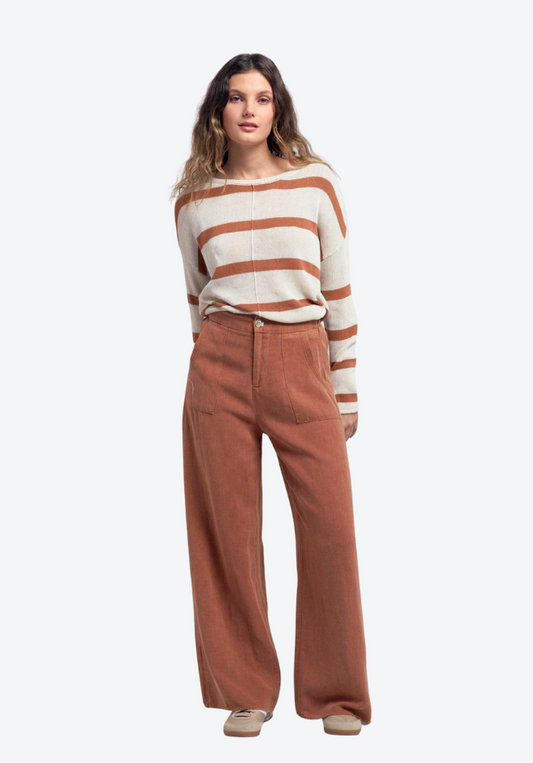 Woman wearing a striped sweater and brown pants on a white background