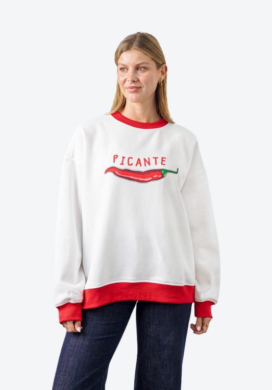 Woman wearing a white sweatshirt with red accents and 'PICANTE' text and pepper graphic on a white background