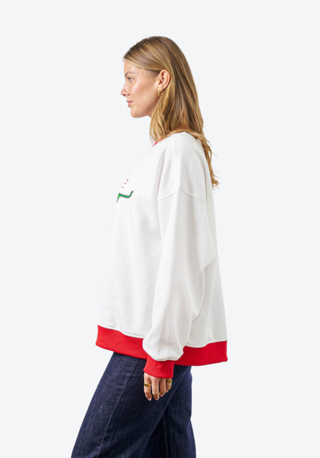 Woman wearing a white sweatshirt with red trim and a green logo on a white background