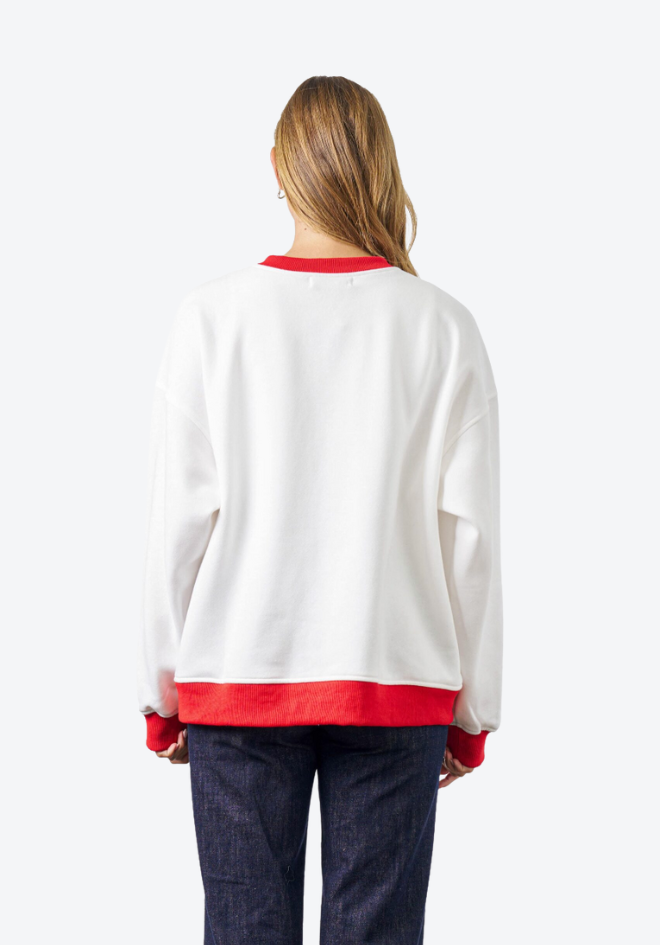 Woman wearing a white sweater with red trim on a white background