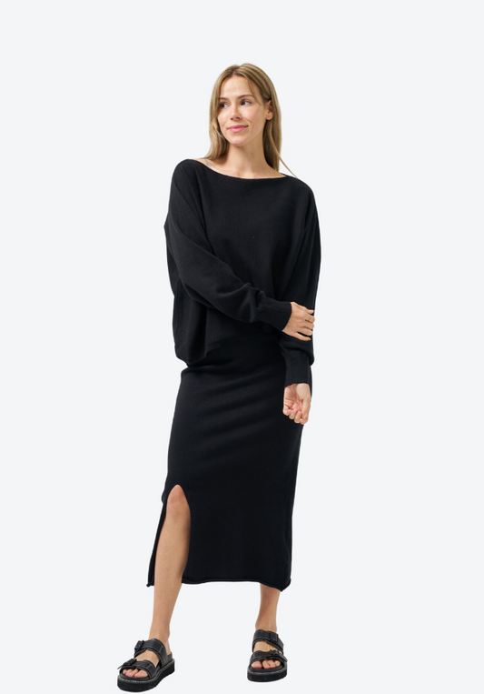 Woman wearing a black dress with a slit on a white background