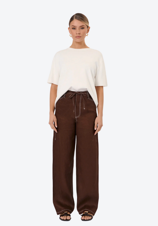 Woman wearing a white top and brown pants on a white background