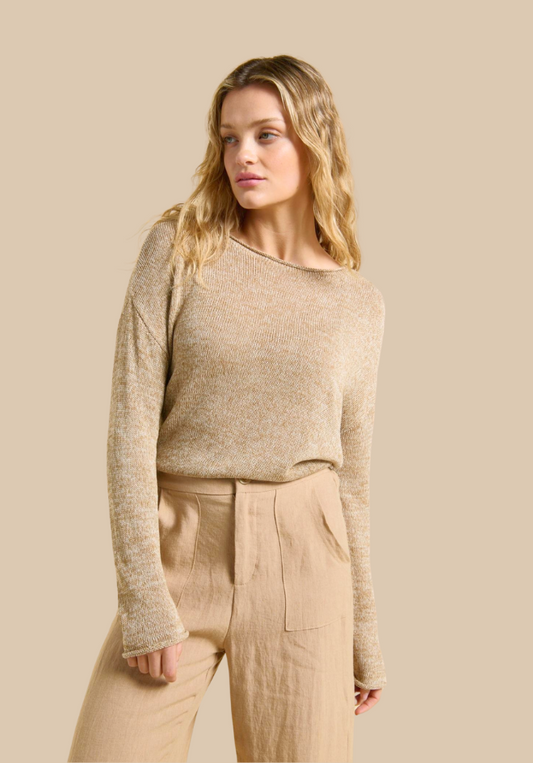 Woman wearing a beige sweater and pants against a beige background