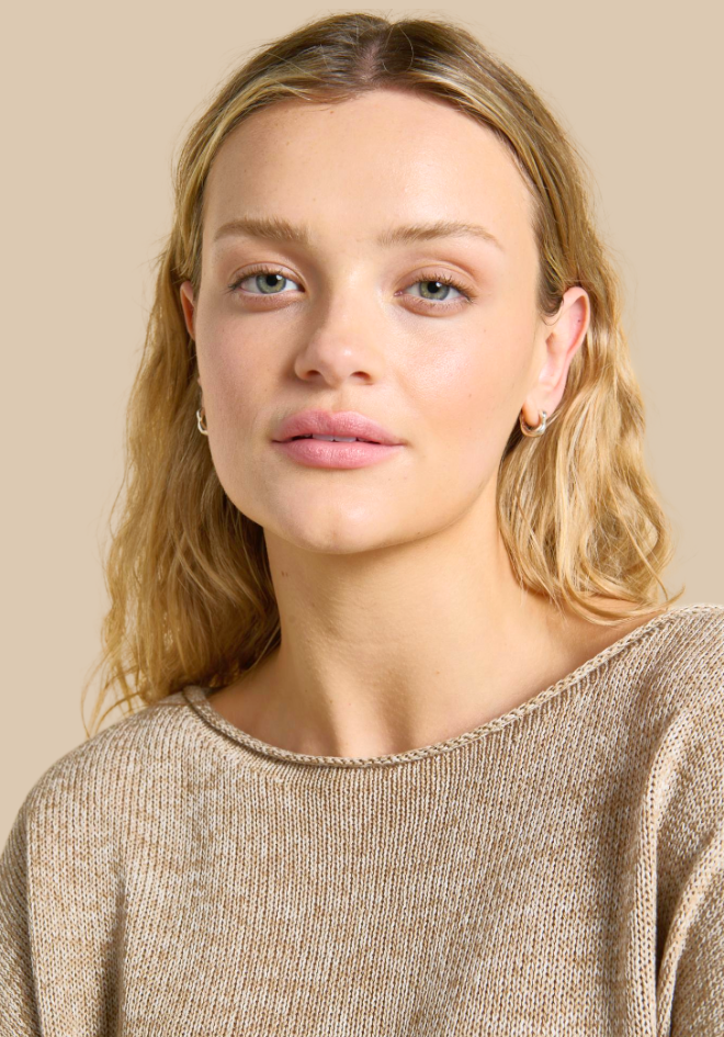 Woman wearing a beige sweater against a beige background