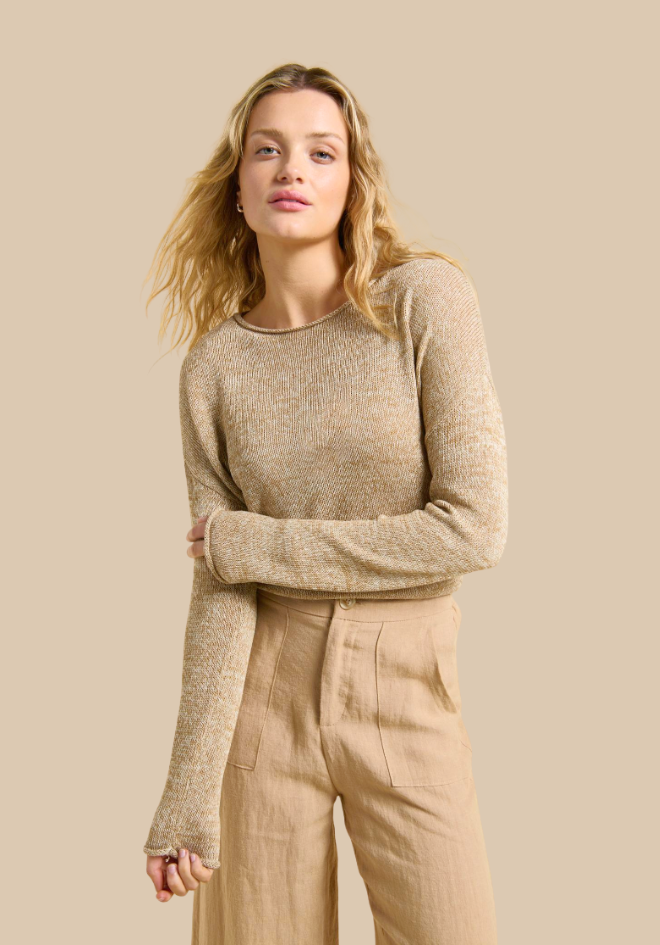 Woman wearing a beige sweater and pants against a beige background