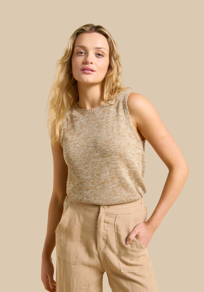 Woman wearing a beige sleeveless top and pants against a beige background