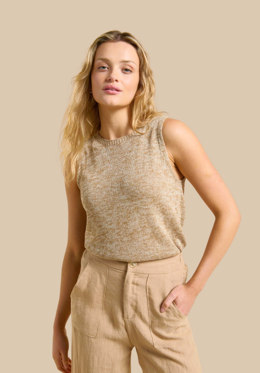 Woman wearing a beige sleeveless top and pants against a beige background