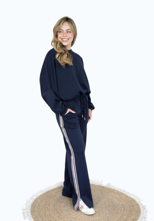 Woman wearing a navy tracksuit with white stripes on a white background