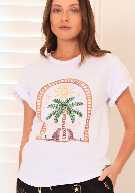 Woman wearing a white t-shirt with a palm tree and cat graphic design.