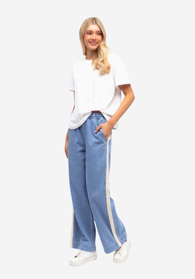 Woman wearing a white top and blue jeans with white stripes on a white background