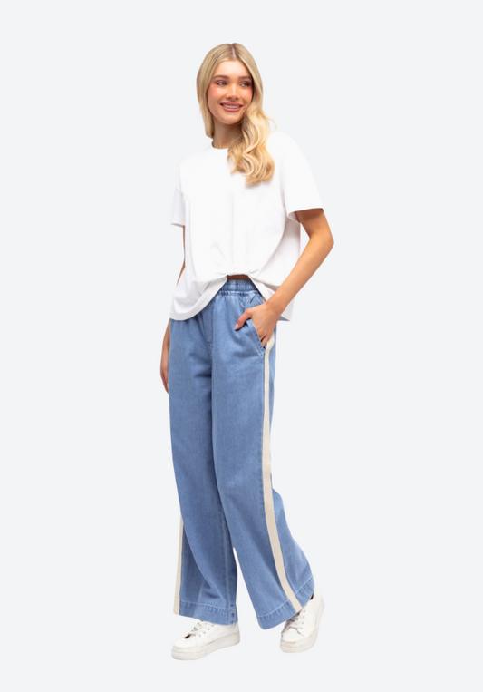 Woman wearing a white top and blue jeans with white stripes on a white background