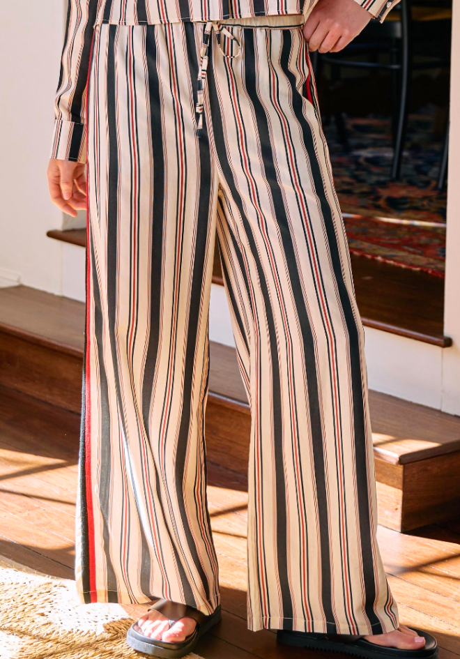 Person wearing a striped outfit with wide-leg pants indoors.