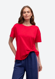 Woman wearing a red top and blue pants with a white background
