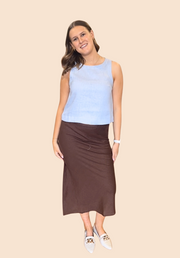Woman wearing a brown sleeveless top and satin skirt on a beige background