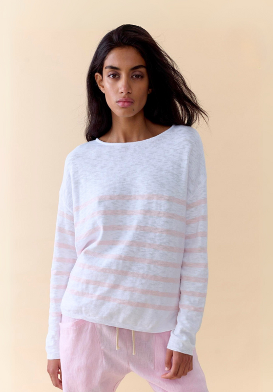 Woman wearing a white and pink striped sweater against a beige background