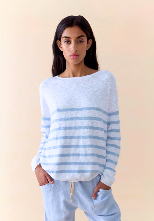 Woman wearing a light blue and white striped sweater against a beige background